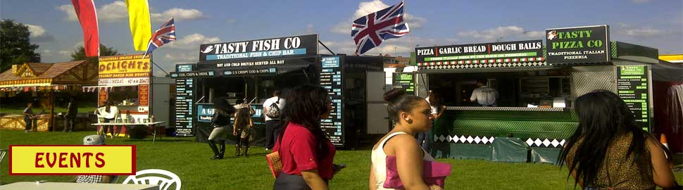 Traditional fish and chip stall at outdoor event in the UK with visitors and festive flags.
