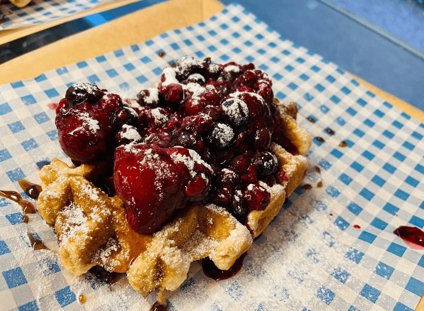 Fresh Belgian waffle with mixed berry compote and powdered sugar, perfect for catering events.