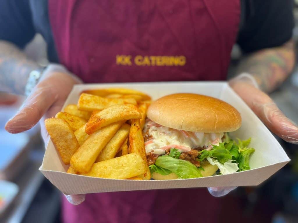 Fresh grilled chicken burger with crispy chips served in eco-friendly tray at KK Catering.