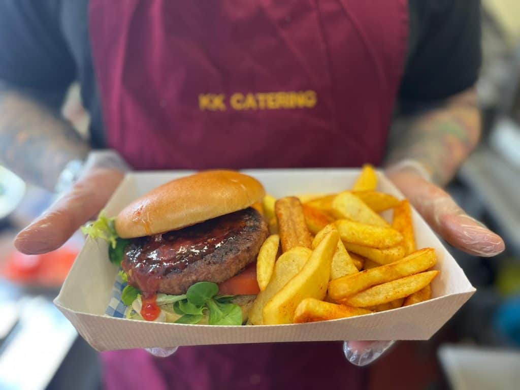 Juicy beef burger with fries, served in a disposable tray, offered by KK Catering for events and parties.