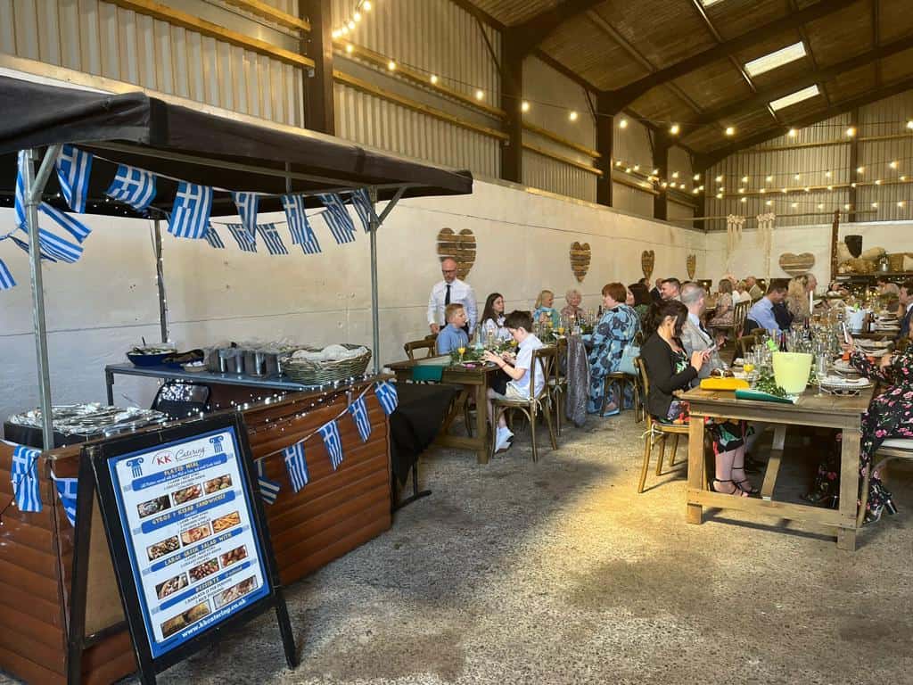 Delicious Greek-inspired catering setup at a wedding with guests enjoying traditional dishes.