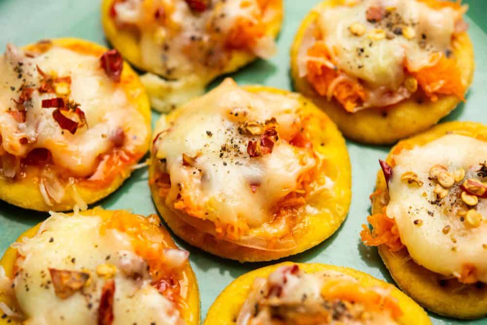 Mini cheesy pizza bites with bacon and vegetables, perfect for catering events and parties.