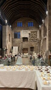 Elegant wedding reception in historic stone venue with catering dessert table, high vaulted ceilings.