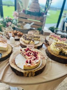 Freshly baked cheesecakes and desserts displayed on rustic wooden slabs at KK Catering event.