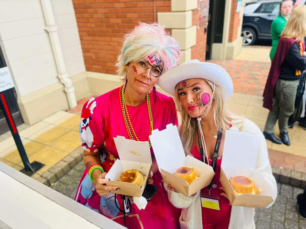 Colourful women holding pie and mash at outdoor company event