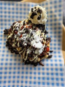 Creamy ice cream sundae with chocolate drizzle and whipped cream, served on checkered paper for dessert comfort.
