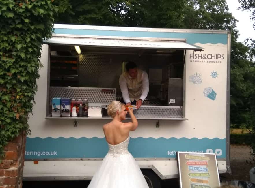 Brightly lit fish and chips food truck serving fresh seafood in the UK, ideal for catering events and outdoor parties.