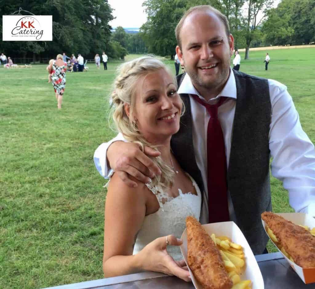 Freshly prepared fish and chips served outdoors at a wedding reception with happy guests.