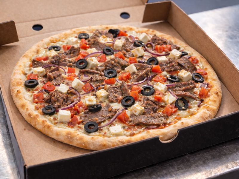 The Greek gourmet pizza with white sauce, kebab meat, tomatoes, onions, olives, feta and mozzarella from KK Catering.