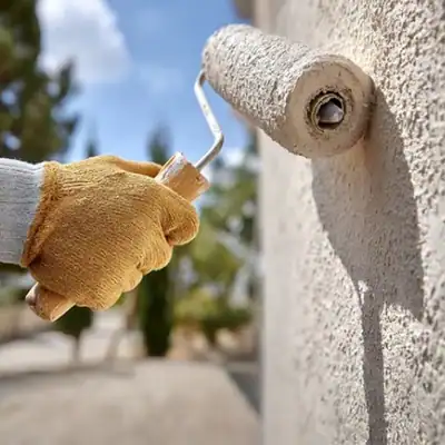 Brush applying textured white paint or plaster to a wall for home decor or renovation projects.