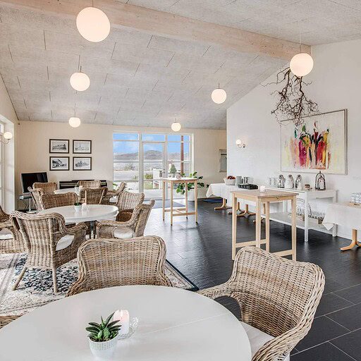 Nordisk badehotel indendørs område med moderne design, rattanstole, kunstværk og afslappet atmosfære.