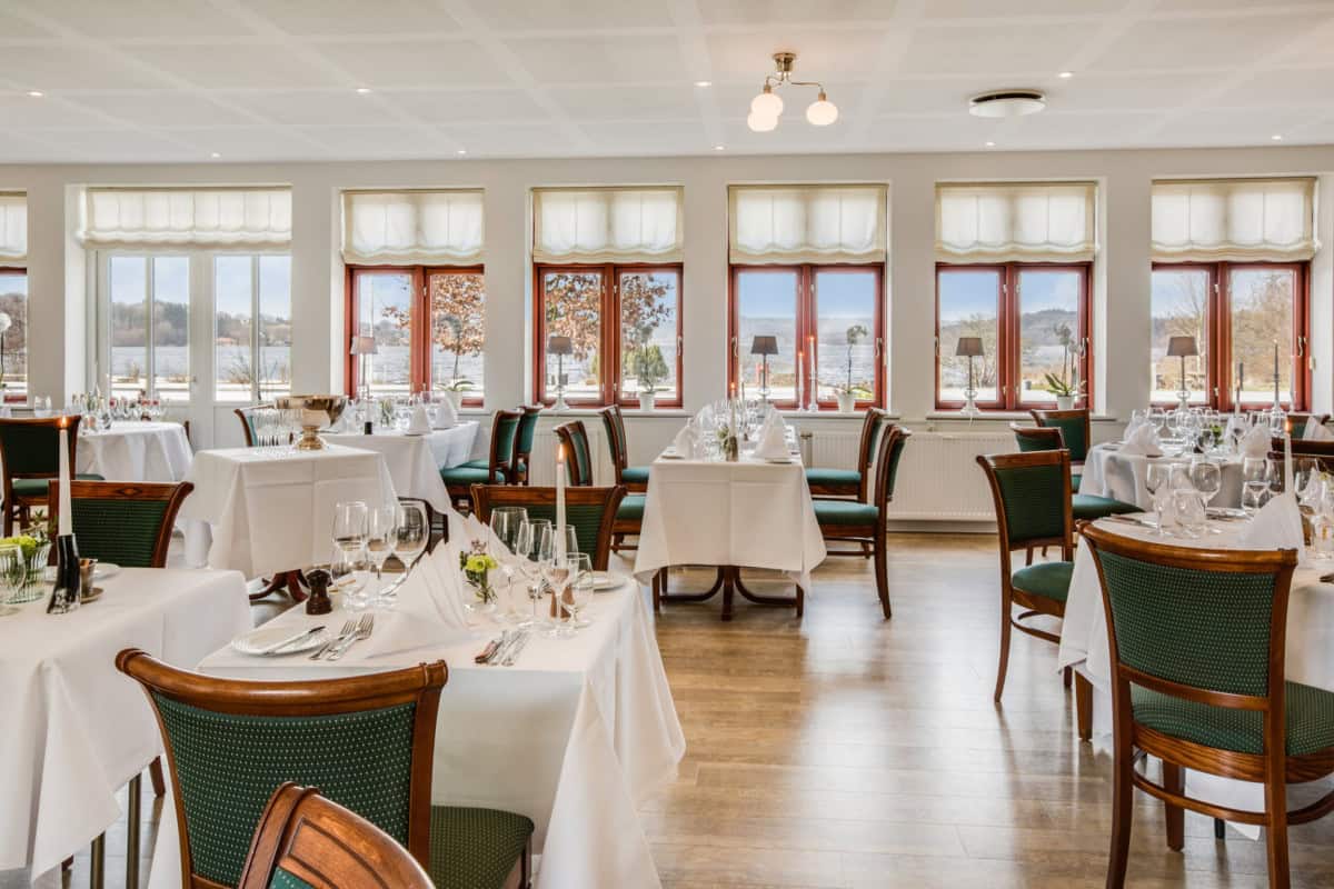 Moderne badehotelsal med store vinduer og udsigt over vandet, klar til elegante middage og events.