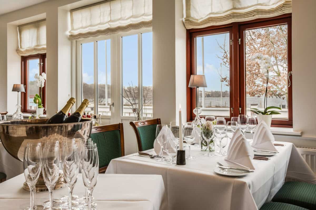 Eksklusivt middagslokale med udsigt over vandet på Knudhule Badehotel, elegant borddækning og romantisk atmosfære.