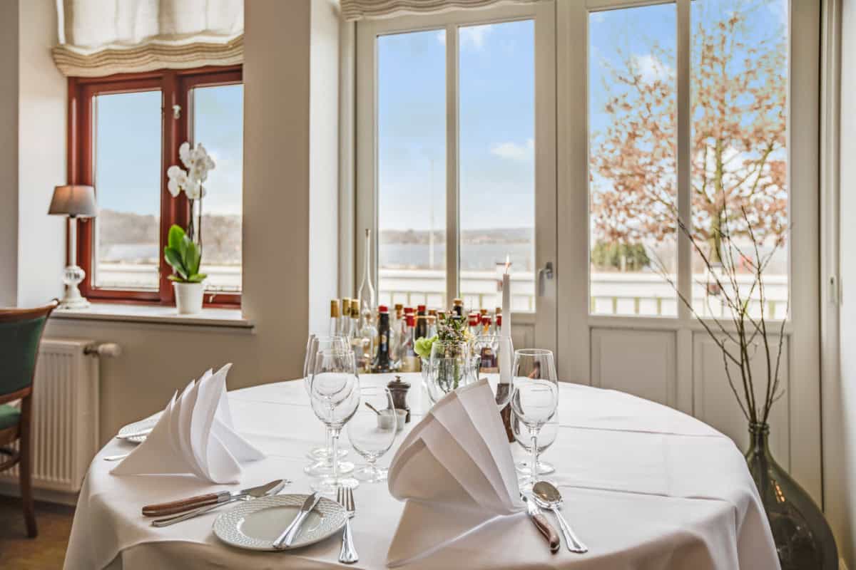 Luksus spisestue med udsigt over fjord og forårsliljer, perfekt til brunch eller fest hos Knudhule Badehotel.