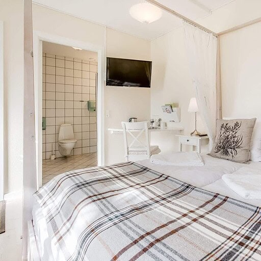 Sengelinned i hyggeligt hotelværelse på Knudhule Badehotel med udsigt over badehotellets komfortable interiør.