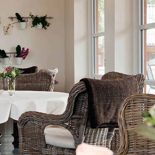 Lavest strandspiseområde med komfortable wængestole og blomsterdekorationer.