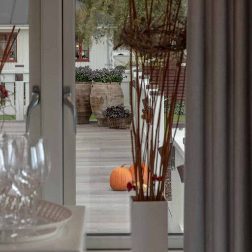 Eksklusiv badehotelindretning med glas, lanterner og høstdekorationer på terrassen.