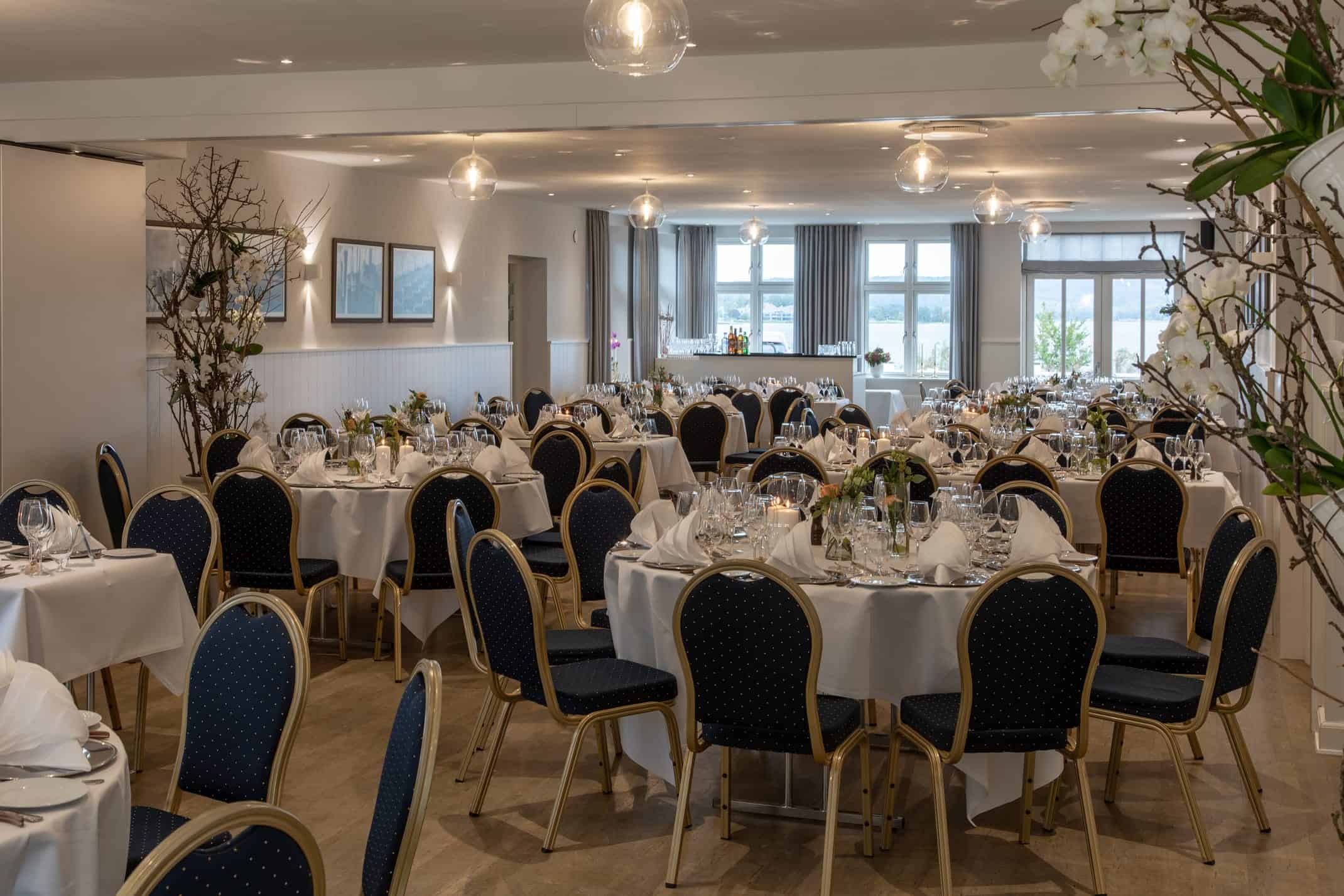 Elegant festlokale med bord dækket til buffet, perfekt til konfirmationer og festlige lejligheder på Knudhule Badehotel.