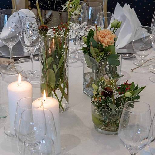 Dekorativt bord med blomsterarrangementer og stearinlys til event på Knudhule Badehotel.