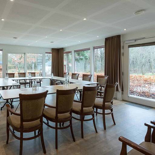 Lyst og indbydende mødelokale på Knudhule Badehotel med store vinduer og hyggelig atmosfære.