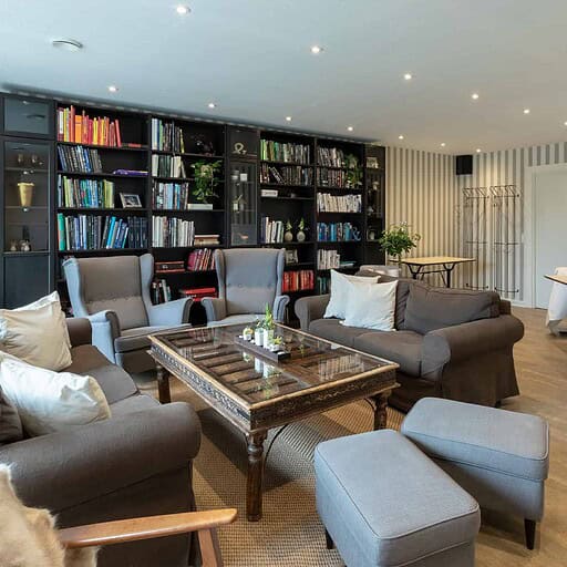 Hyggeligt bibliotek og loungeområde på Knudhule Badehotel med komfortable stole og bogreoler.