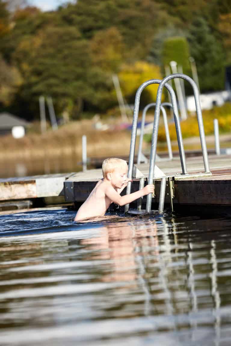 Børne i vandet ved Knudhule Badehotel, naturskønt fredeligt badeområde i Danmark.