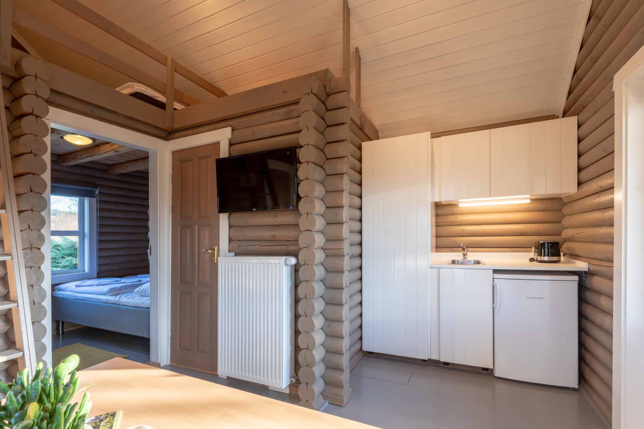 Rustikt indrettet badehotelværelse med hvide skabe og træinteriør på Knudhule Badehotel.