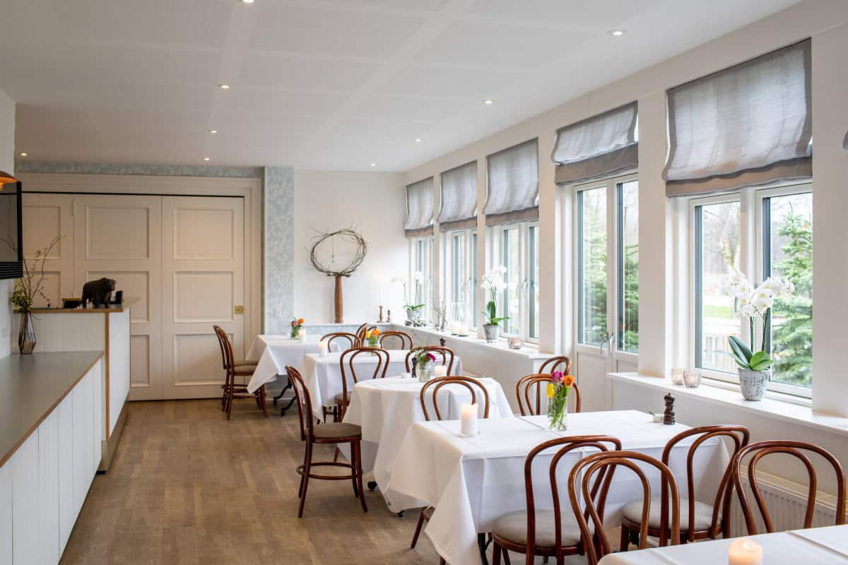 Lækkert spisestueområde med store vinduer og hyggelig atmosfære på Knudhule Badehotel.
