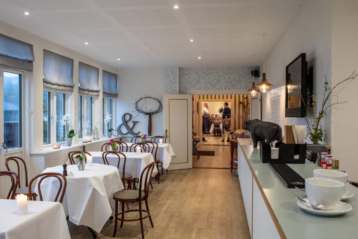 Hyggeligt badehotelindretning med elegant spisestue og moderne design, perfekt til afslapning ved vandet.