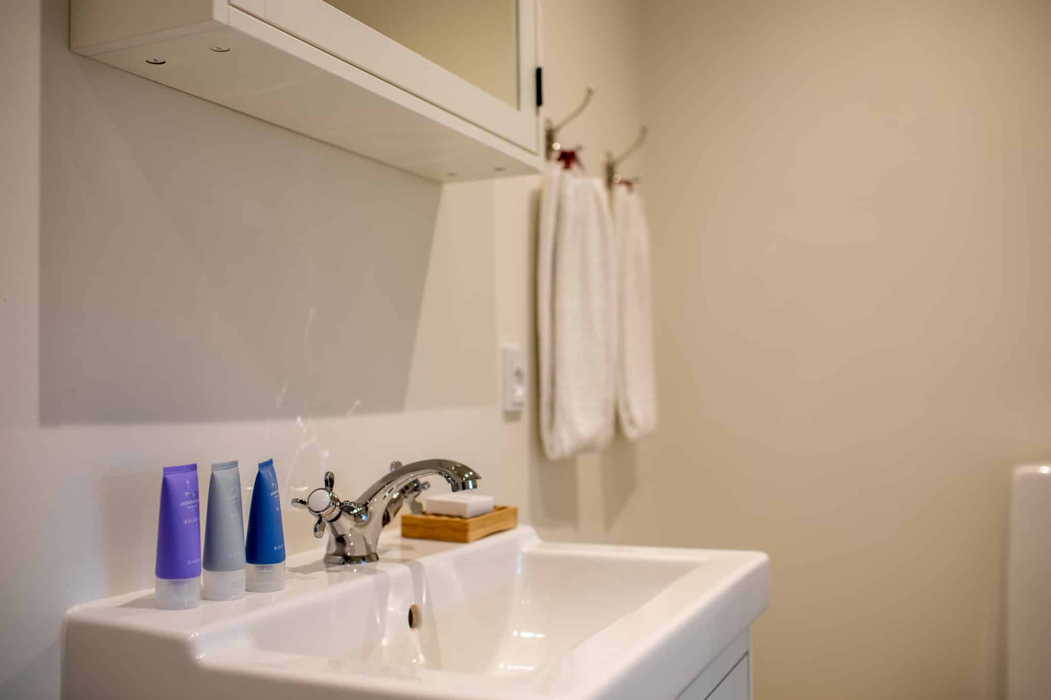 Håndvask med shampoo og håndklæder på badeværelse, Knudhule Badehotel.