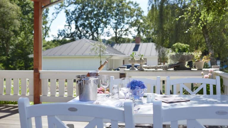 Solrig terrasse med udsigt over grønne omgivelser ved Knudhule Badehotel.
