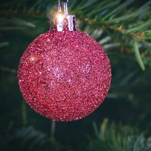 Glitterrød juleballon på grantræ, perfekt til julestemning på Knudhule Badehotel.