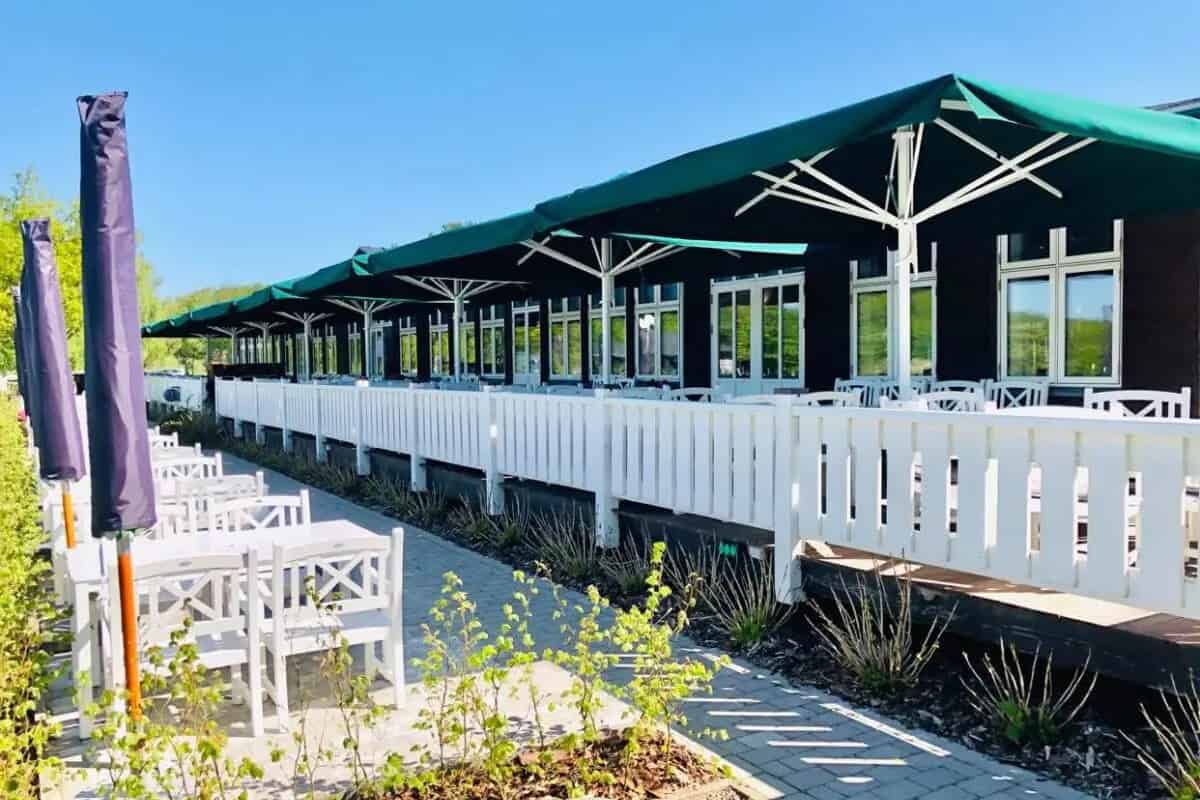 Smuk udendørs restaurant ved Knudhule Badehotel med havudsigt og solbeskyttende parasoller.