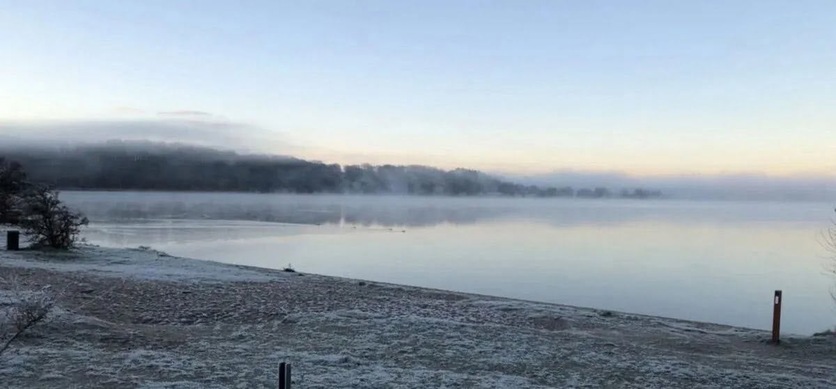 Fredeligt vinterpanorama ved Knudhule Badehotel med udsigt over roligt vand og sneklædt kystlinje.