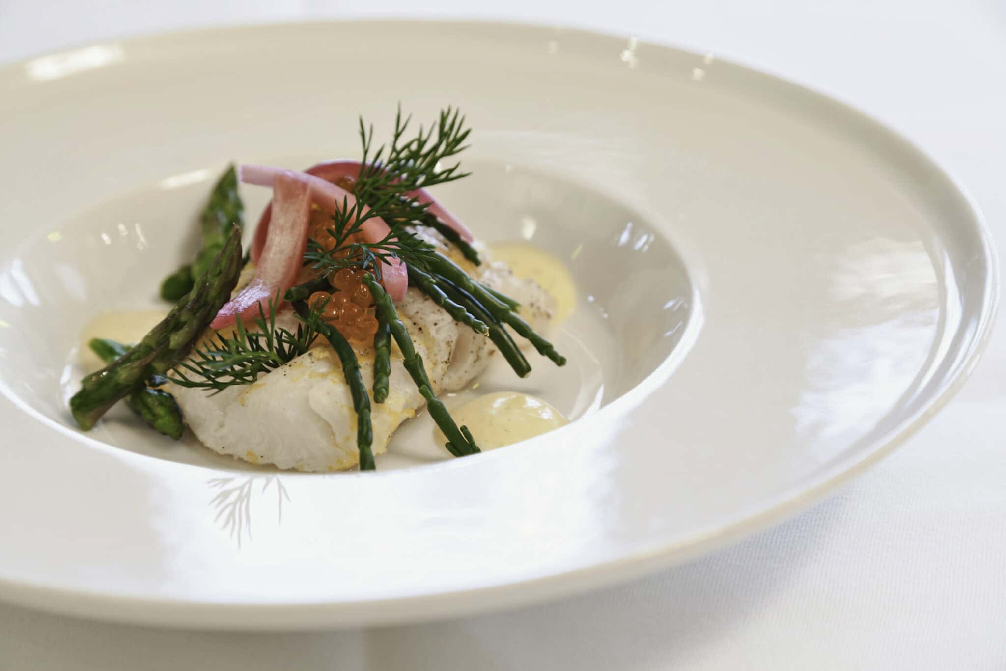 Fiskeret med asparges, urter og æggecreme fra Knudhule Badehotel. Eksklusiv gourmetoplevelse i naturskønne omgivelser.