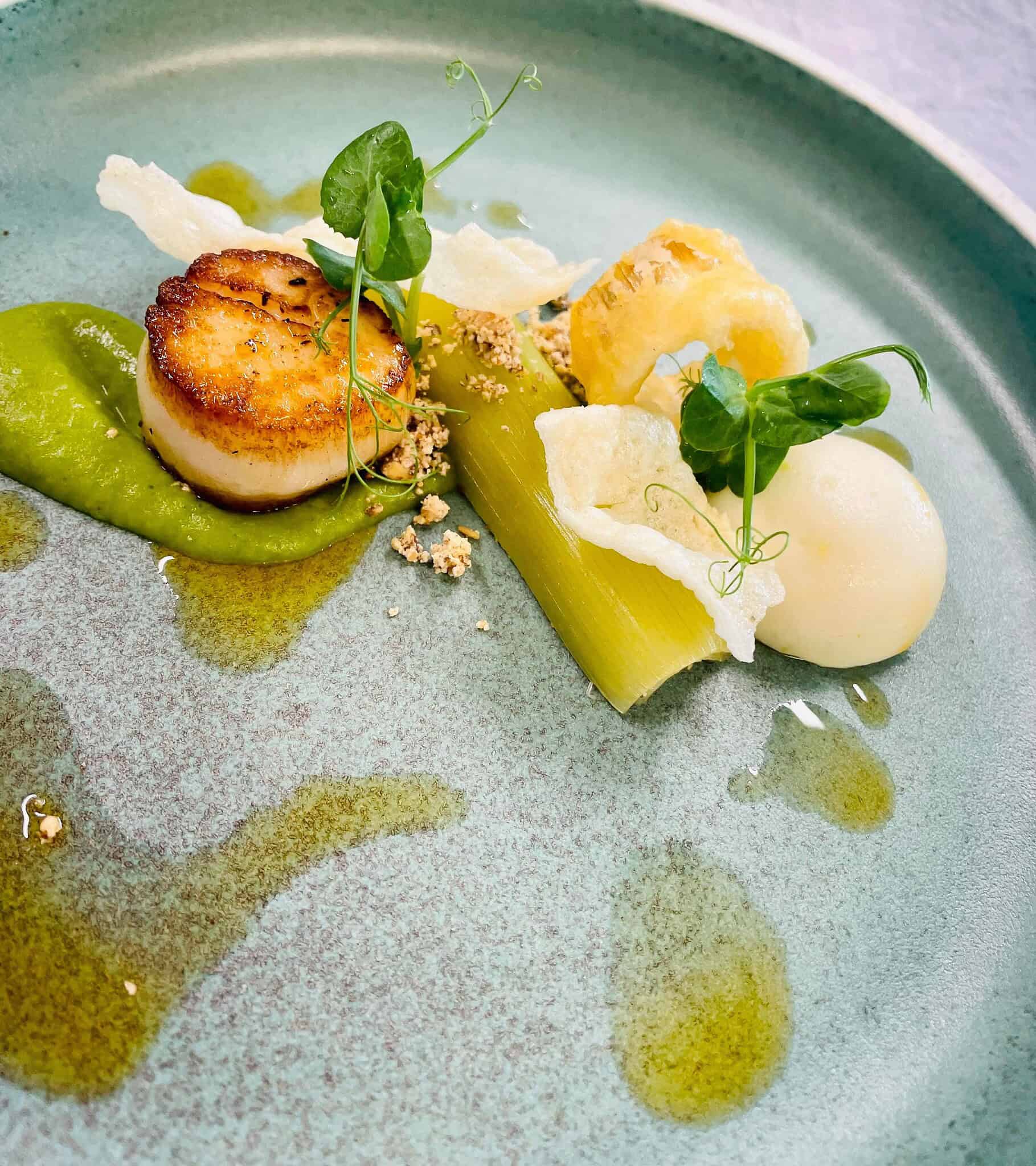 Eksklusiv fiskerett med grønne grøntsager og elegant anretning på Knudhule Badehotel.