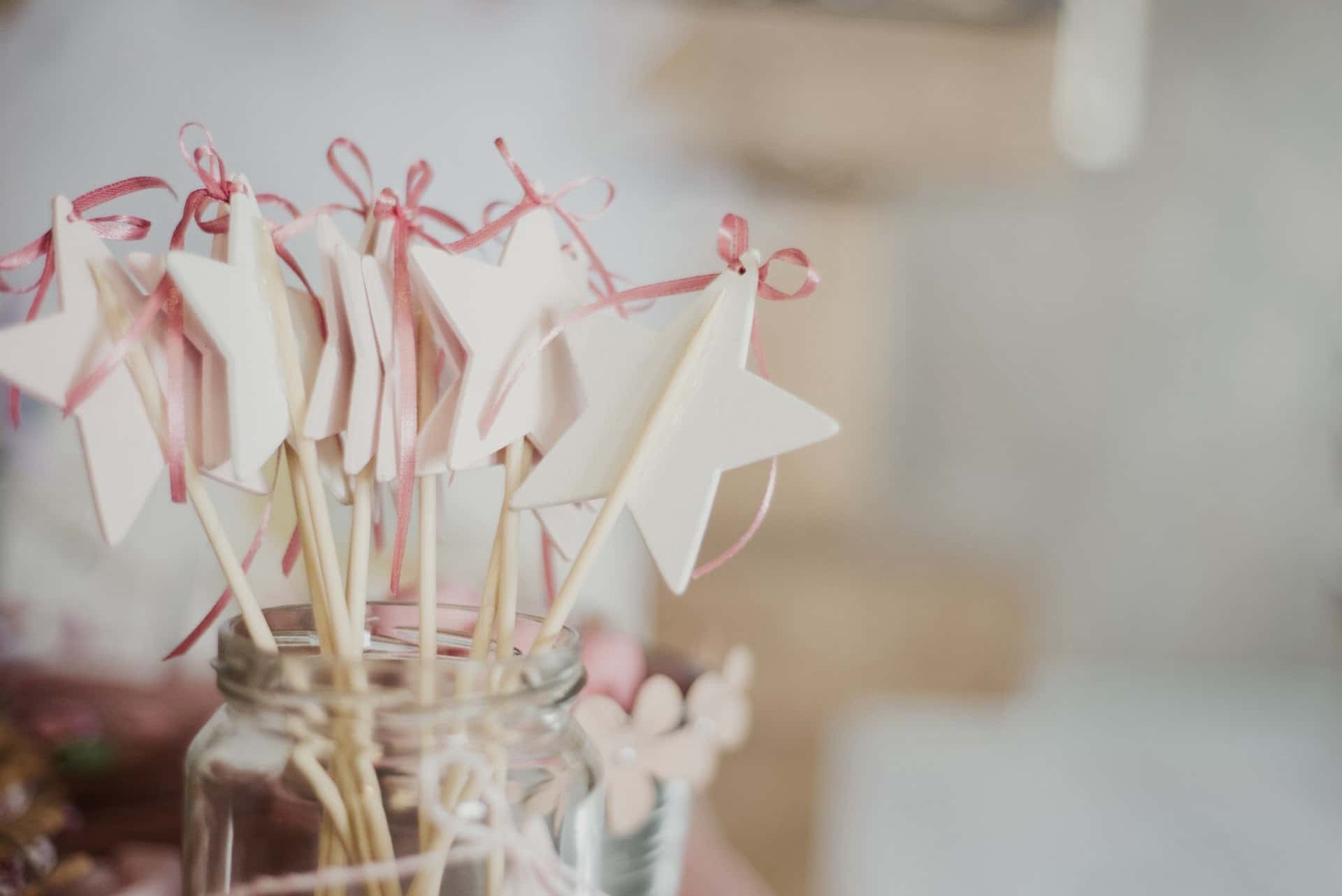 Bløde hvidkbejdsede stjernepynt på pind i glas med pink bånd efterårskage, dekorativt element.