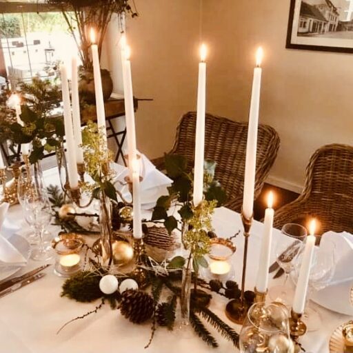 Håndlavet juleborddekoration med stearinlys og gran, perfekt til hygge på Knudhule Badehotel.