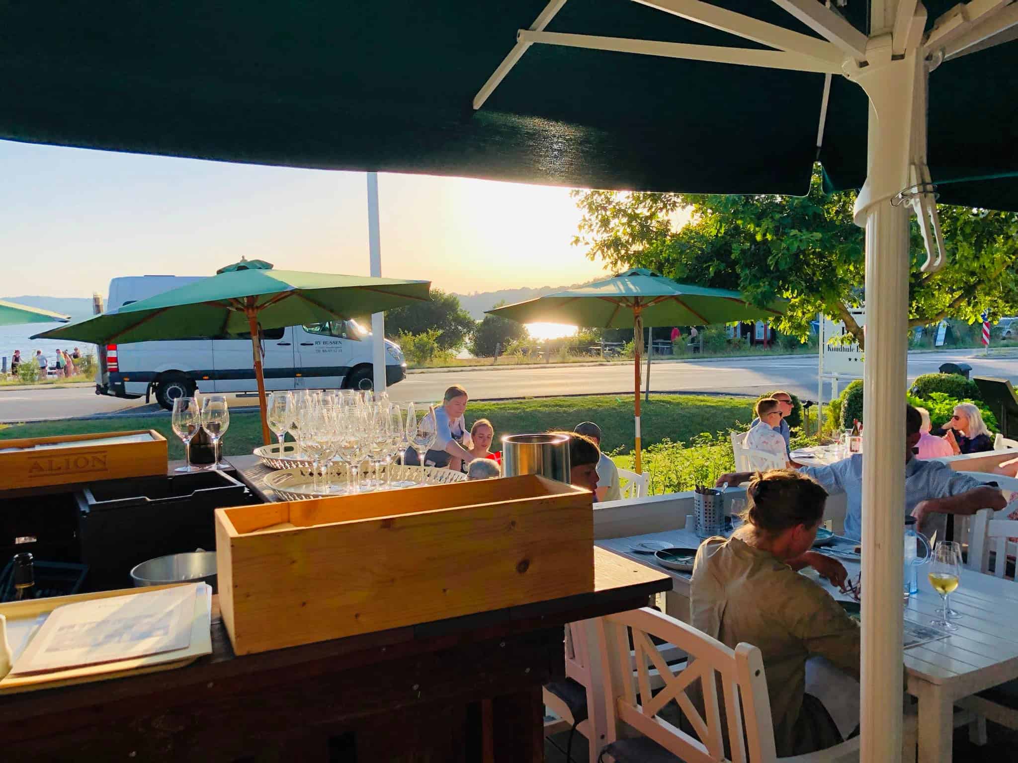 Selvbetjent udeservering med glaseret bestik og parasoller ved Knudhule Badehotel.