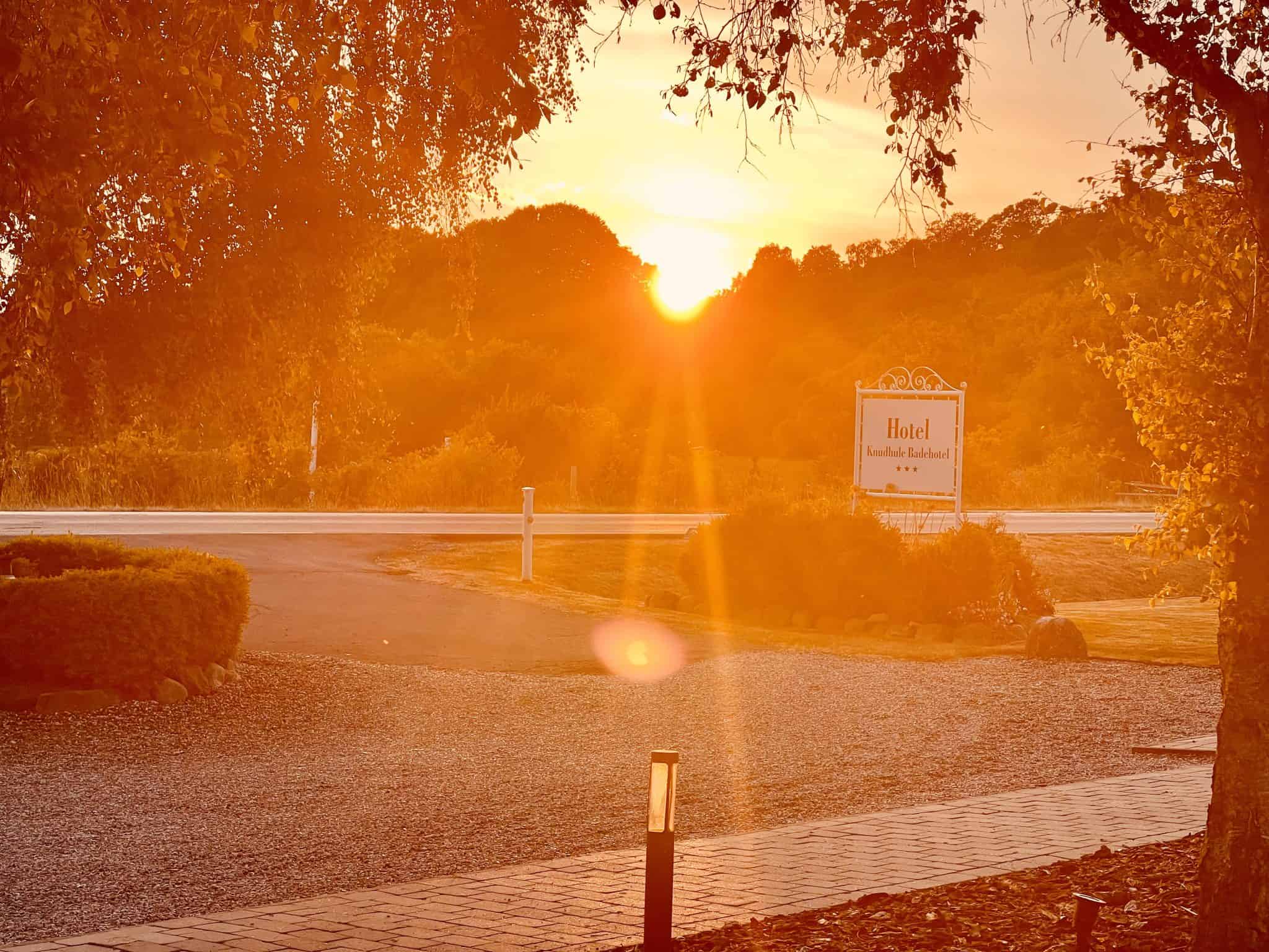 Fredelig hotelindgang ved solnedgang på Knudhule Badehotel i naturskønt omgivelser.