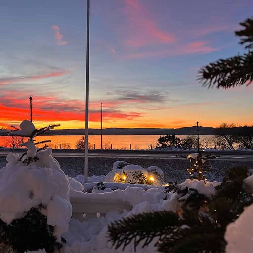 Billedet viser en smuk vinterhimmel ved Knudhule Badehotel med farverige solnedgangs- og skymønstre over vandet.
