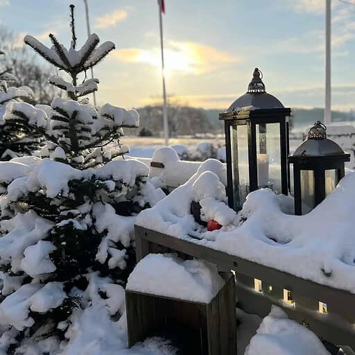 Snøklædt udendørs område ved Knudhule Badehotel med hyggelige lanterner og vinterlandskab.