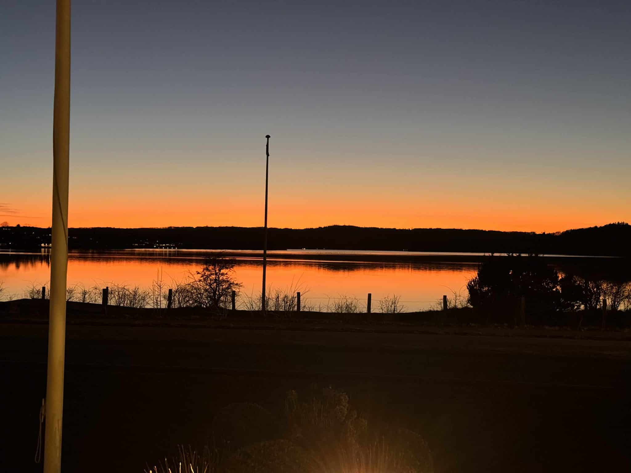Rolig aftenstemning ved Knudhule Badehotel, smuk solnedgang over fjorden i Danmark.