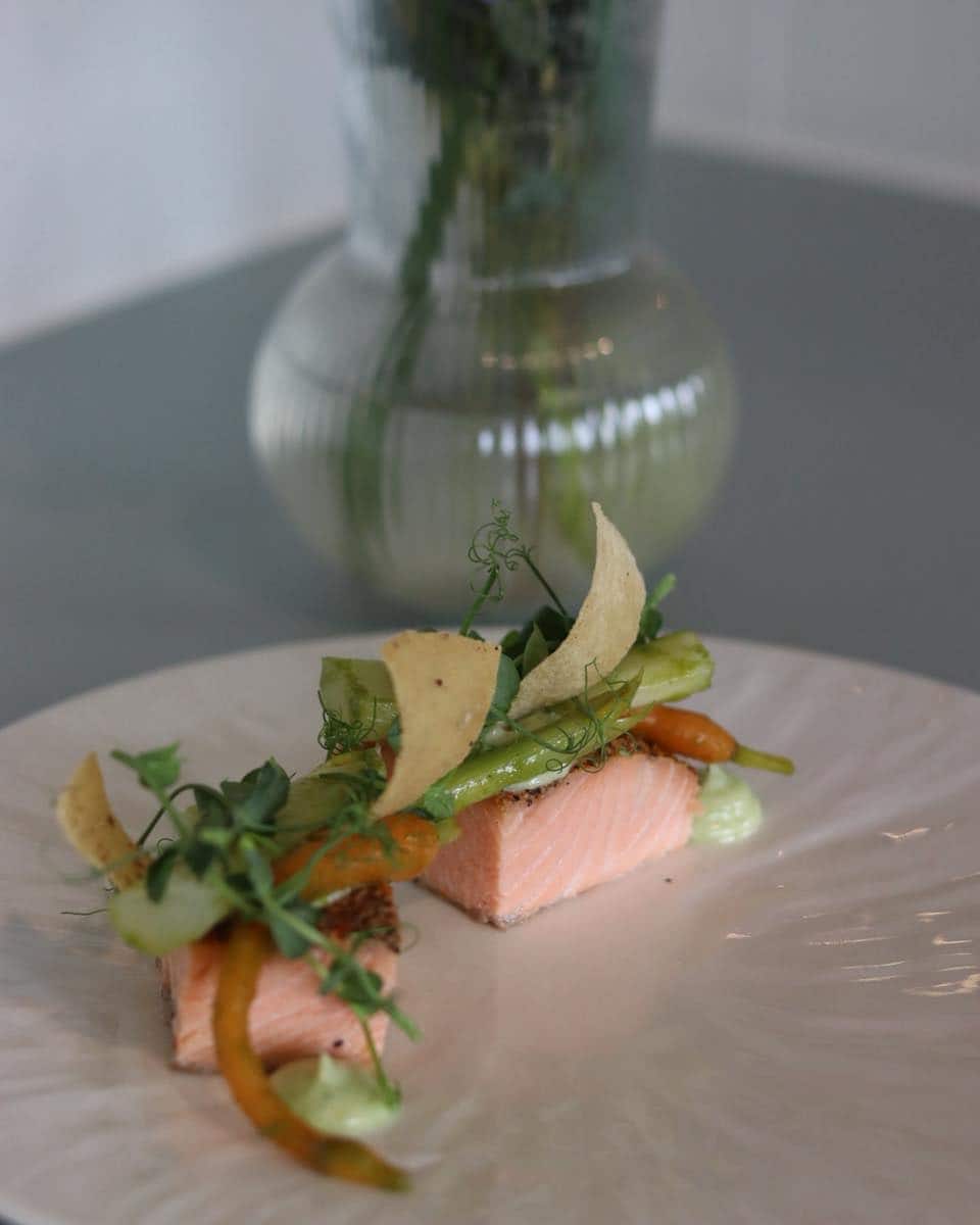 Fiskeret med grøntsager og sprøde elementer på fin tallerken.