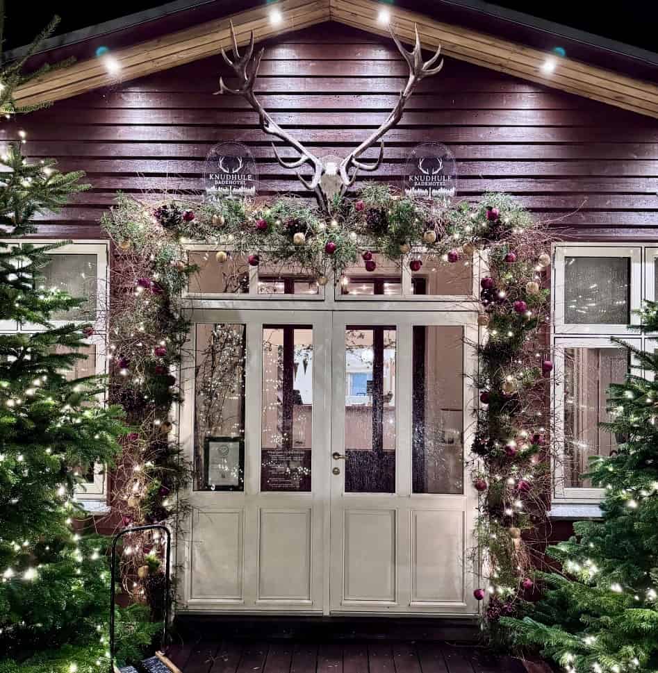 Glædeligt juleudsmykket badehotel med lysende træer og ornamenter.