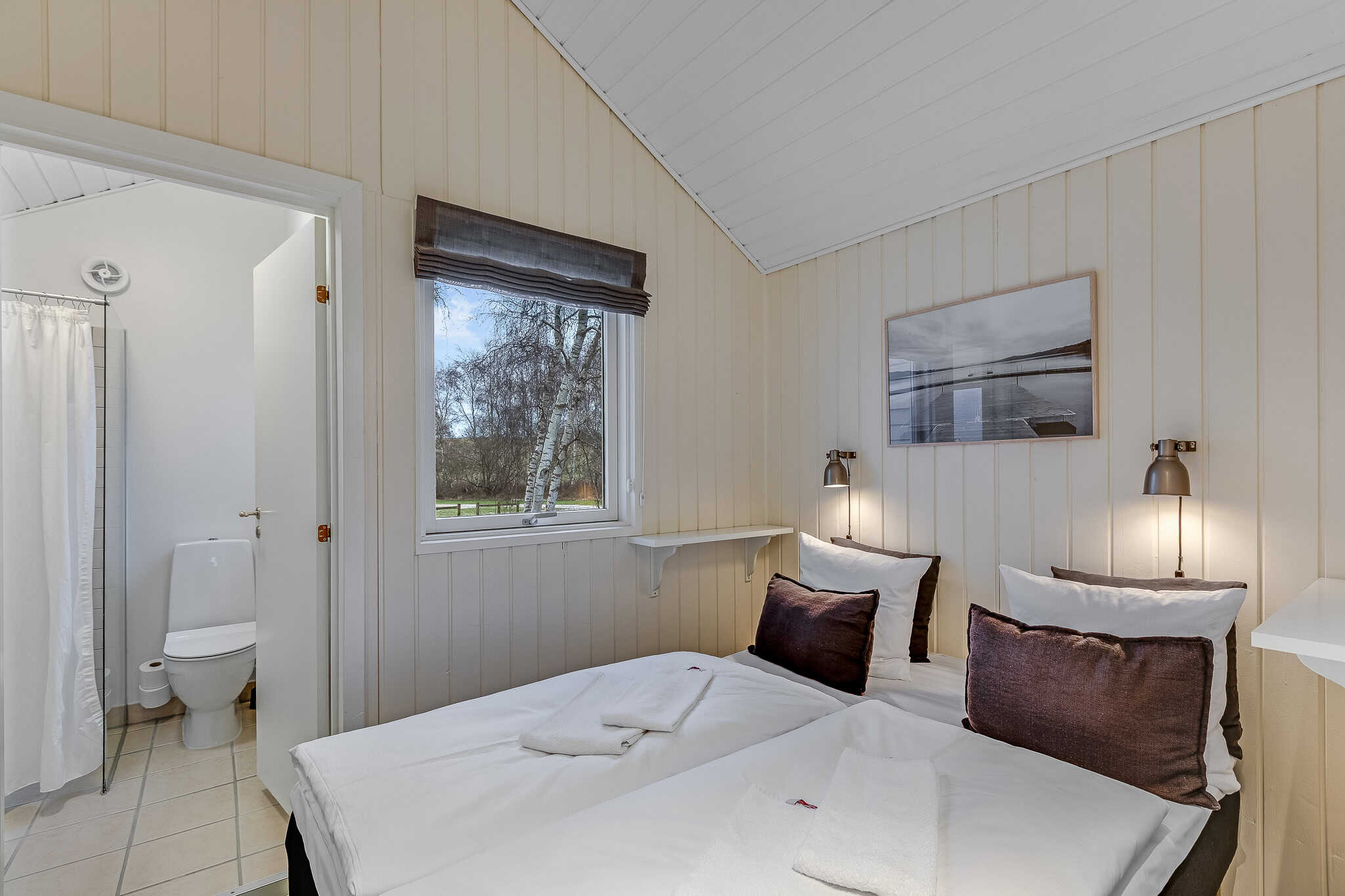 Hyggeligt badehotelværelse med soveværelse og privat badefaciliteter på Knudhule Badehotel.