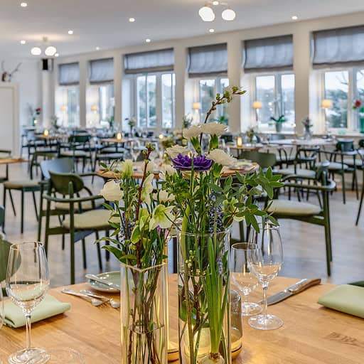 Højkvalitets indendørs restaurant med store vinduer og elegant borddækning på Knudhule Badehotel.