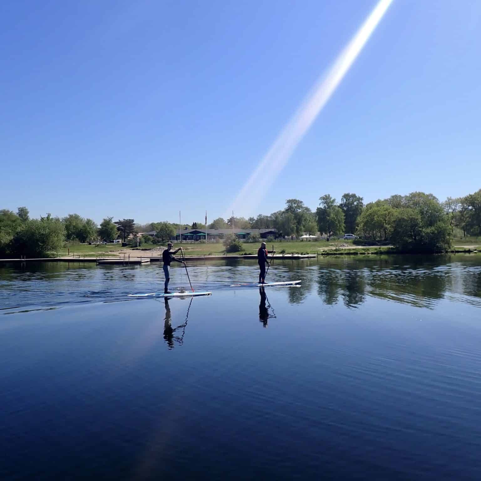 Fredelige stand-up paddleboarding aktiviteter på åben sø ved Knudhule Badehotel. Smuk natur og rolig vandoplevelse.