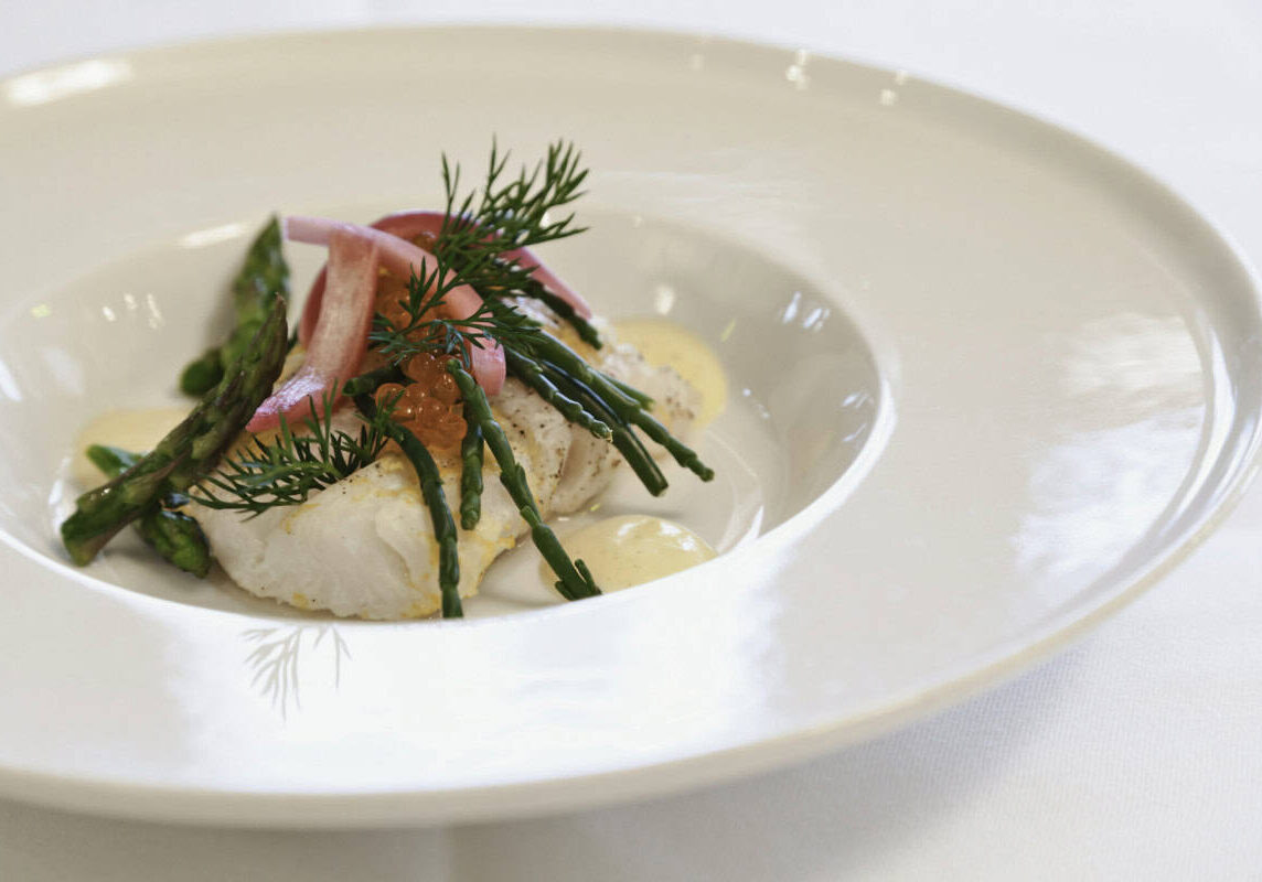 Fiskeret med asparges, urter og æggecreme fra Knudhule Badehotel. Eksklusiv gourmetoplevelse i naturskønne omgivelser.