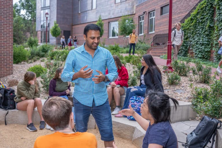 Professor lecturing to two students during an outdoor class.